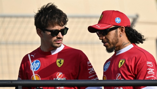 Ferrari's Monegasque driver Charles Leclerc and Ferrari's British driver Lewis Hamilton talk as they take part in the drivers parade for the Bahrain Formula One Grand Prix at the Bahrain International Circuit in Sakhir on April 13, 2025. (Photo by Andrej ISAKOVIC / AFP)